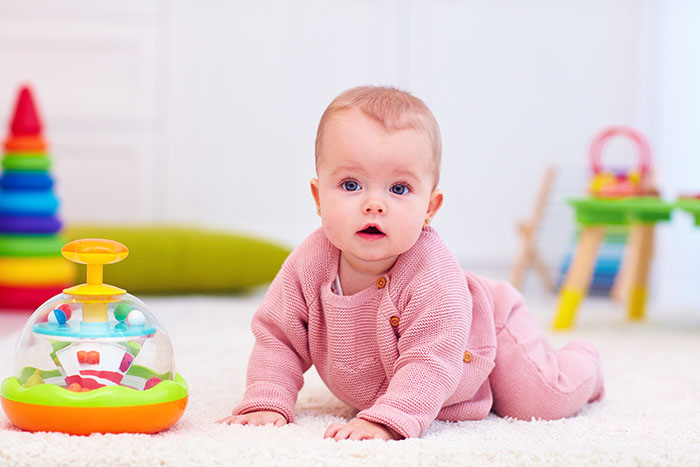 cute little baby girl crawling on the carpet among the development toys at a Preschool & Daycare Serving Carmel, Indiana