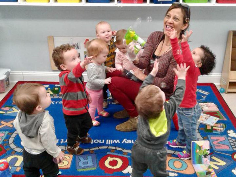 happy teacher and kids playing with bubbles at a Preschool & Daycare Serving Carmel, Indiana