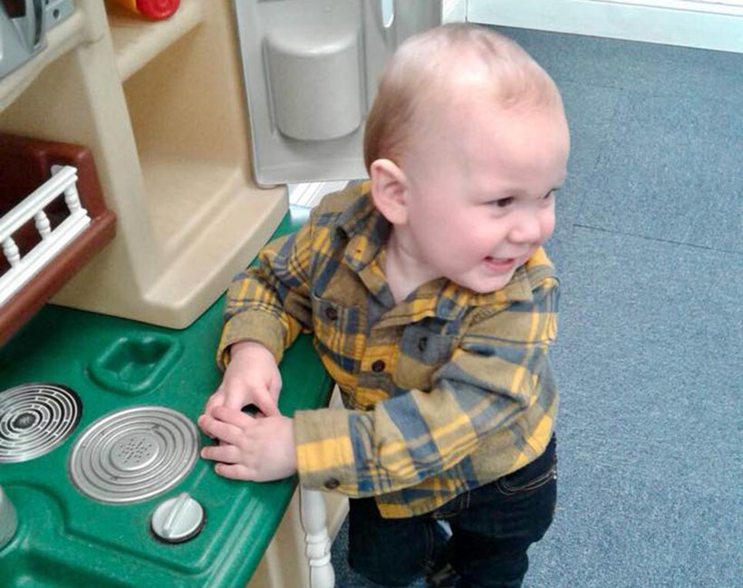 happy toddler in toy kitchen at a Preschool & Daycare Serving Carmel, Indiana