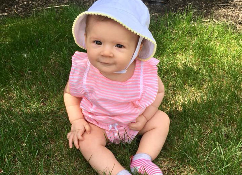 smiling baby sitting on grass outdoors at a Preschool & Daycare Serving Carmel, Indiana